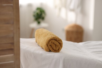 Photo of Rolled towel on massage table in spa center, closeup