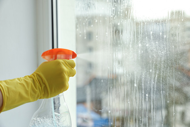 Photo of Woman cleaning window at home, closeup. Space for text