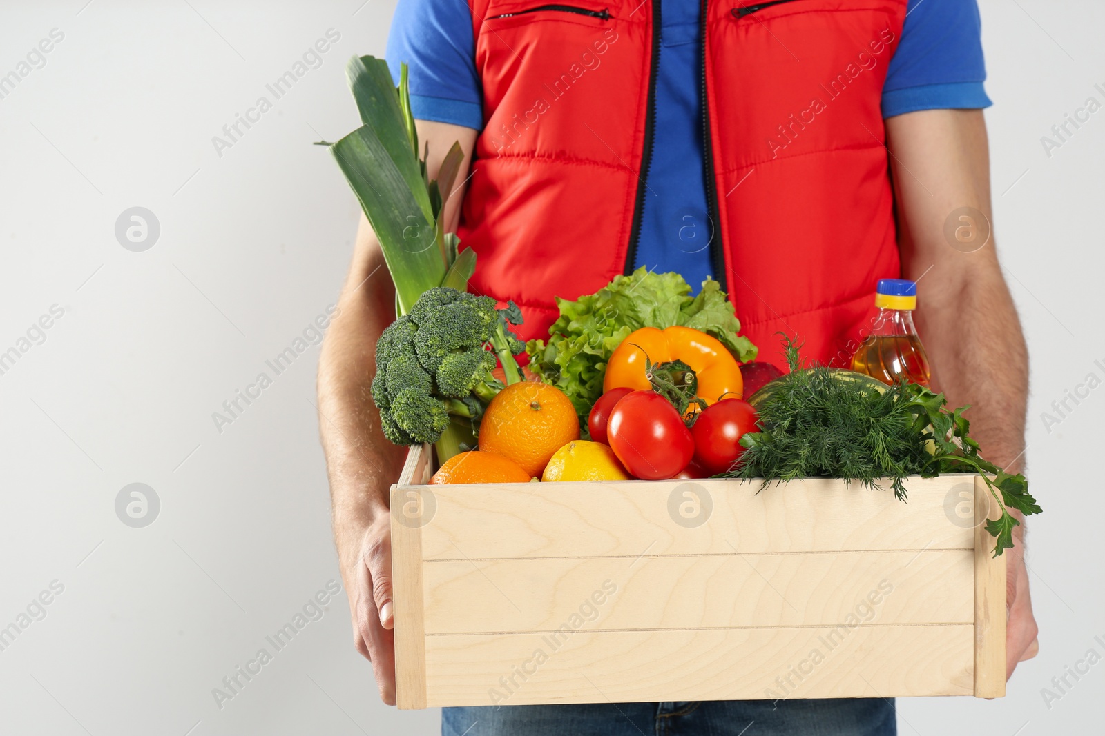Photo of Courier with fresh products on light background, closeup. Food delivery service