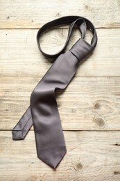 Photo of One necktie on light wooden table, top view