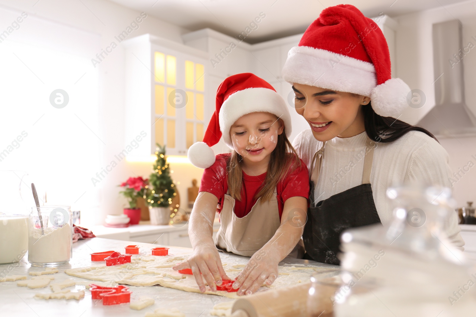 Photo of Mother with her cute little daughter making Christmas cookies in kitchen