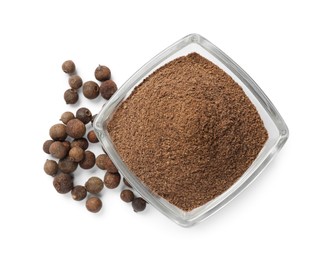 Photo of Ground allspice pepper in glass bowl and grains isolated on white, top view