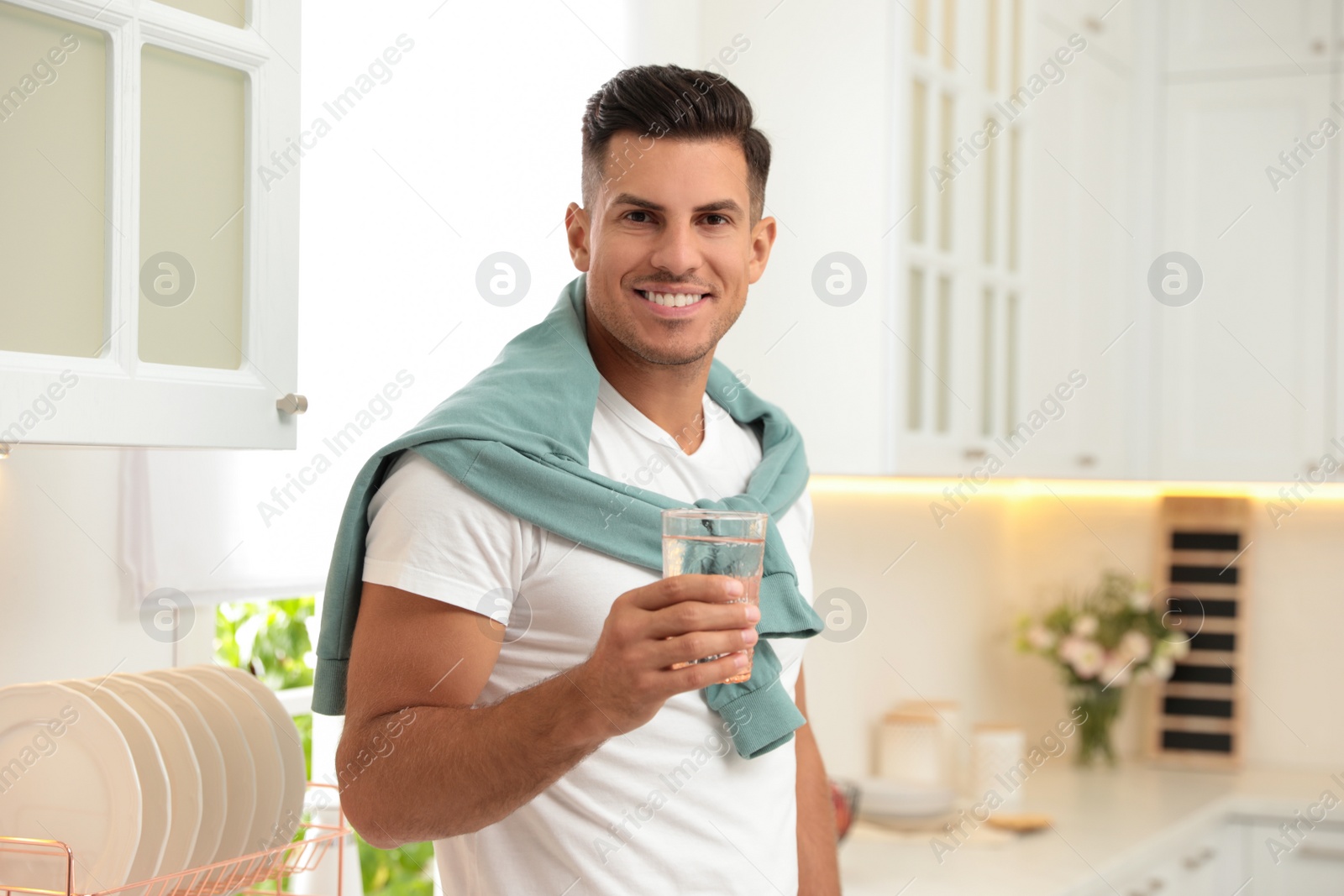 Photo of Man holding glass of pure water in kitchen