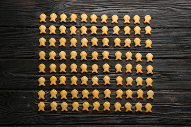 Photo of Delicious fish shaped crackers on black wooden table, flat lay