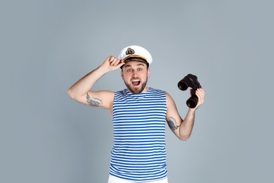 Photo of Emotional sailor with binoculars on light grey background