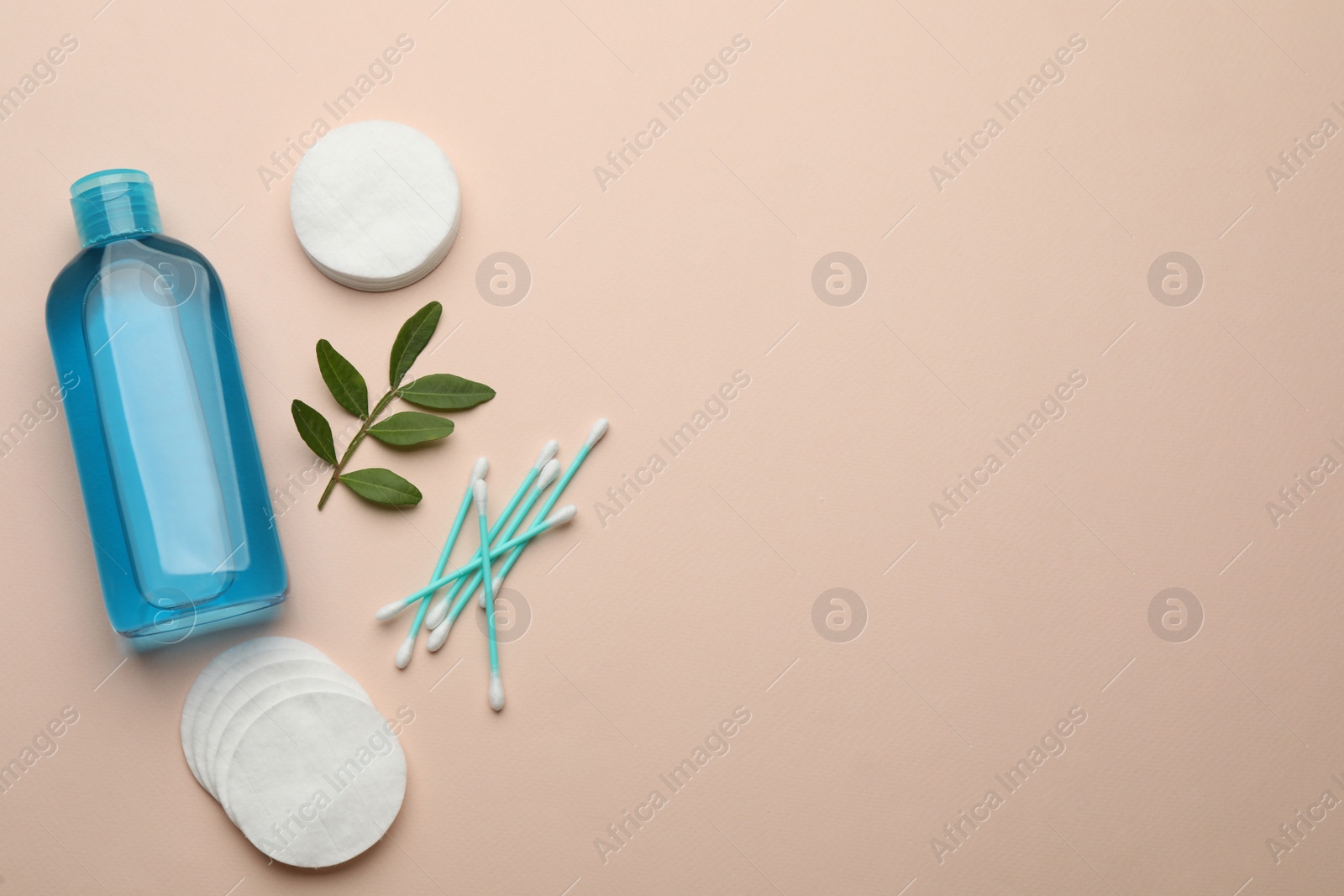 Photo of Cotton pads, swabs, leaves and makeup removal product on beige background, flat lay. Space for text