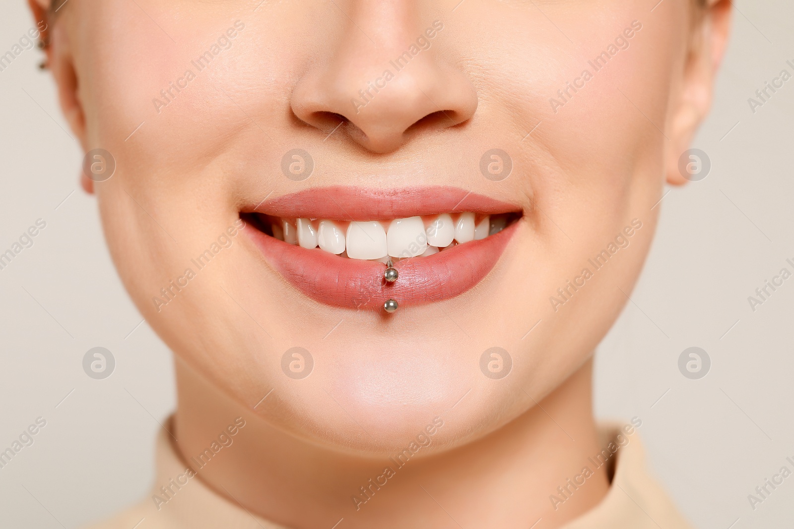 Photo of Young woman with lip piercing on white background, closeup