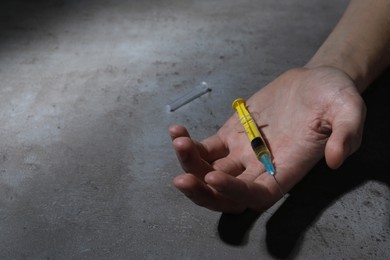 Drug addiction. Man with syringe on grey table, closeup and space for text