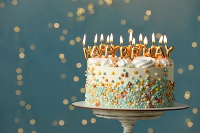 Photo of Beautiful birthday cake with burning candles on stand against festive lights. Space for text