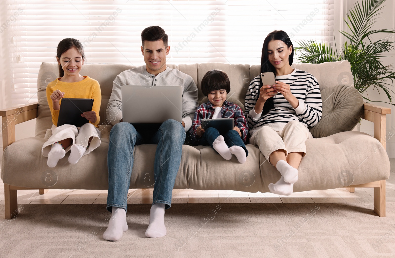 Photo of Internet addiction. Family with different gadgets on sofa at home