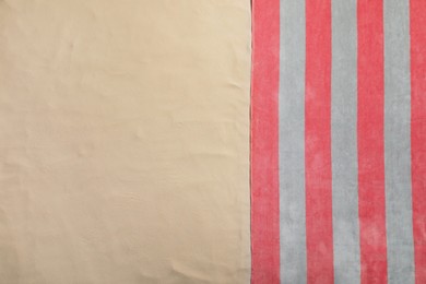 Striped beach towel on sand, top view. Space for text