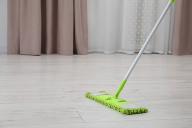 Photo of Cleaning dirty parquet floor with mop indoors. Space for text