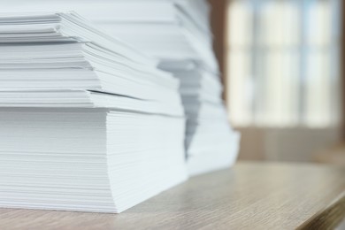 Stacks of paper sheets on wooden table against blurred background, closeup. Space for text