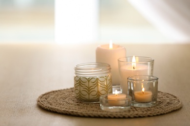 Photo of Beautiful burning candles on table at home. Space for text
