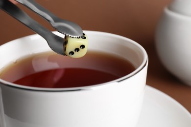 Putting dice instead of sugar cube in tea, closeup