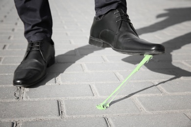 Photo of Man stepping in chewing gum on sidewalk. Concept of stickiness