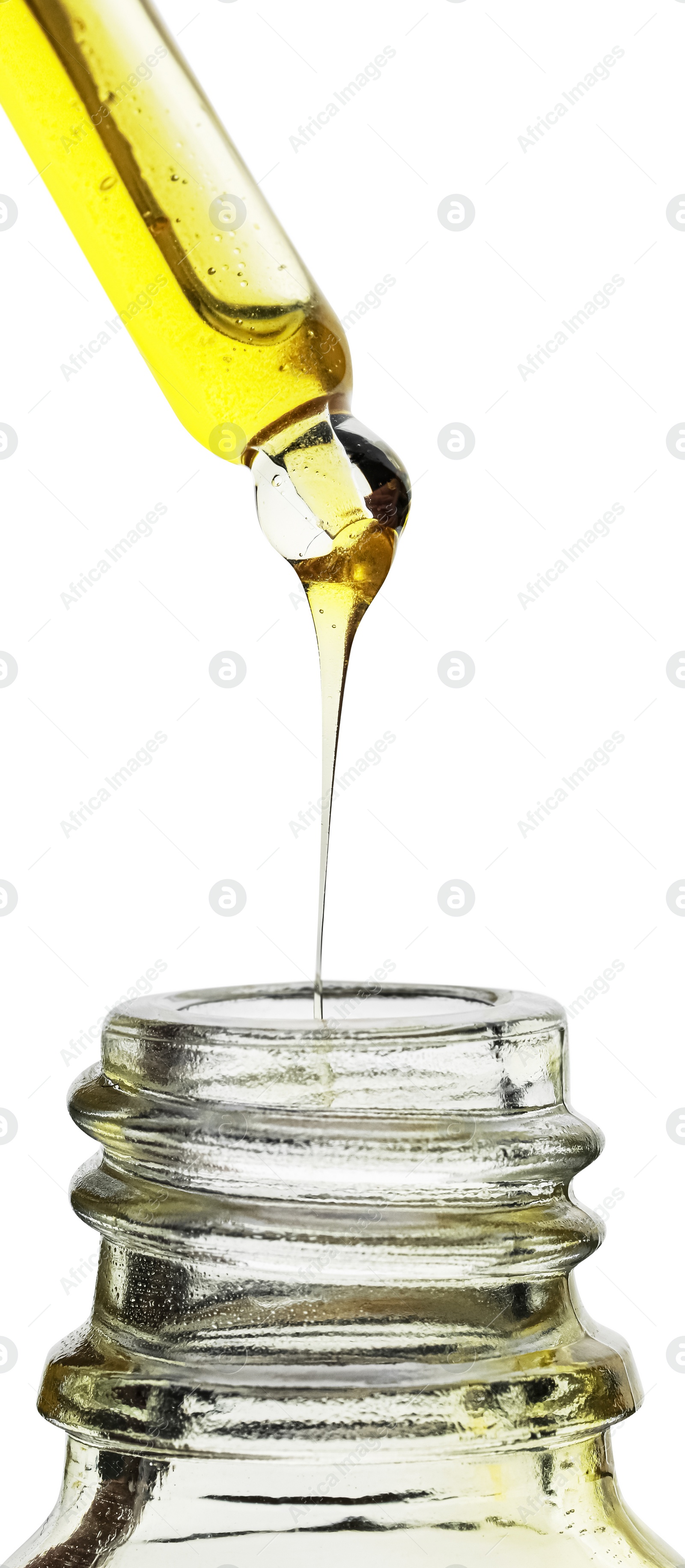 Photo of Dripping yellow facial serum from pipette into glass bottle on white background, closeup