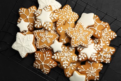 Tasty Christmas cookies with icing on black table, top view