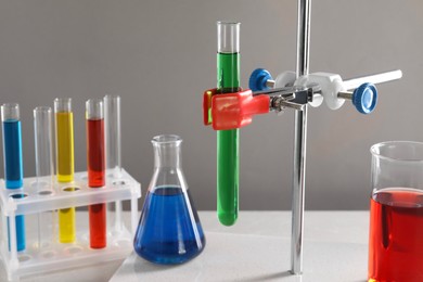 Photo of Retort stand and laboratory glassware with liquids on table against light grey background