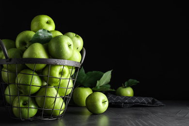 Juicy green apples in metal basket on grey table, space for text
