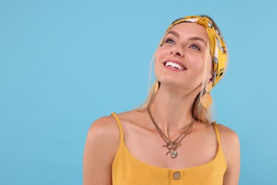 Portrait of happy hippie woman on light blue background. Space for text