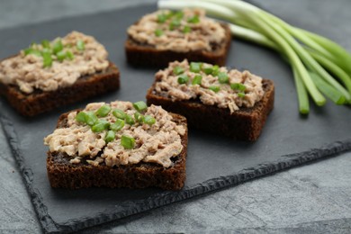 Photo of Tasty sandwiches with cod liver and green onion on light grey table