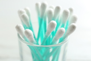 Photo of Glass with cotton swabs on light background, closeup