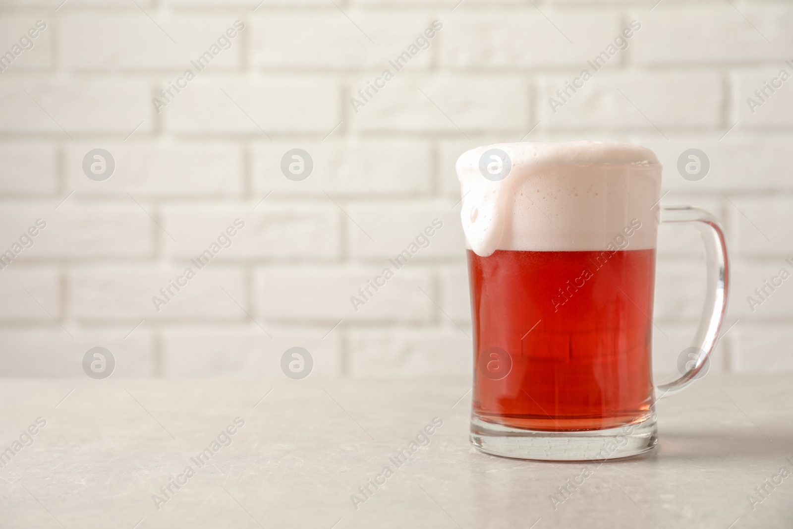 Photo of Glass mug with cold red beer on table