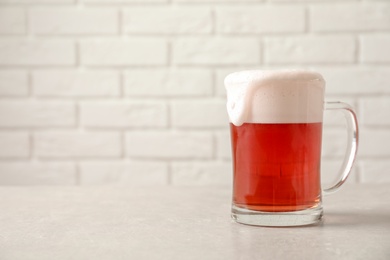 Photo of Glass mug with cold red beer on table