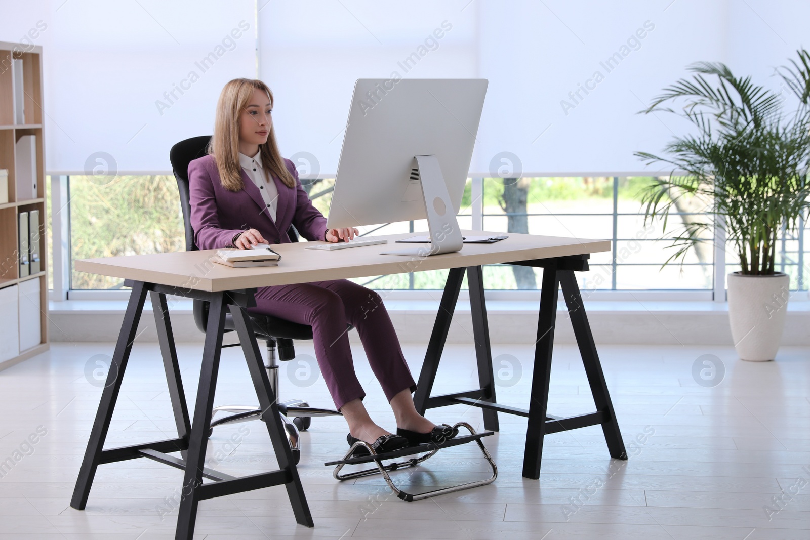 Photo of Woman using footrest while working on computer in office