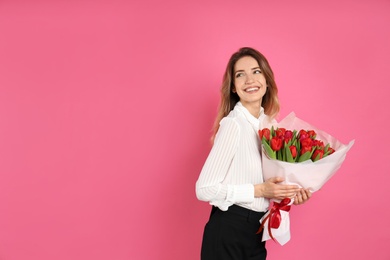 Photo of Happy woman with red tulip bouquet on pink background, space for text. 8th of March celebration