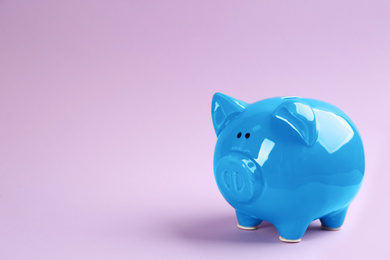 Photo of Blue piggy bank on violet background. Space for text