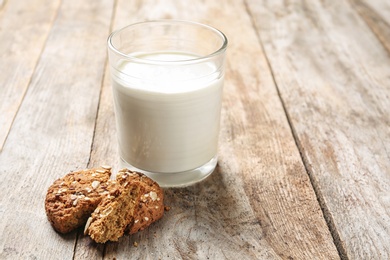 Glass of milk and grain cereal cookies on wooden table. Healthy snack