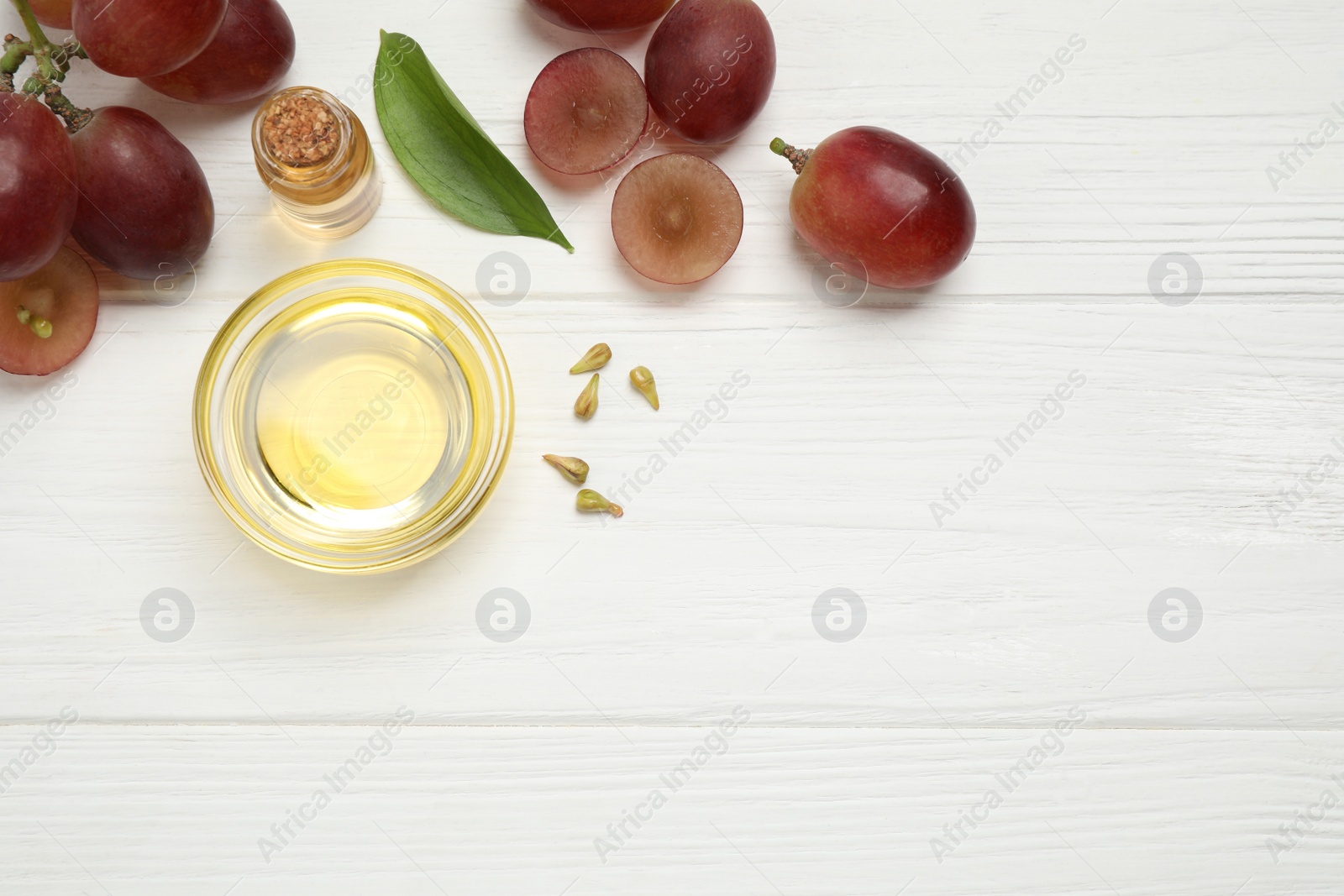 Photo of Flat lay composition with natural grape seed oil on white wooden table, space for text. Organic cosmetic