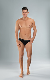 Handsome man in black underwear on light grey background