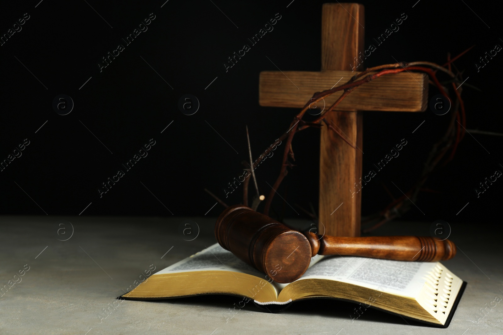 Photo of Judge gavel, bible, wooden cross and crown of thorns on grey table. Space for text