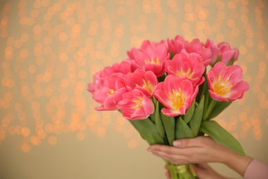 Photo of Girl holding spring tulips on blurred background, closeup with space for text. International Women's Day