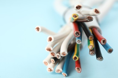 Photo of Many electrical wires on light blue background, closeup