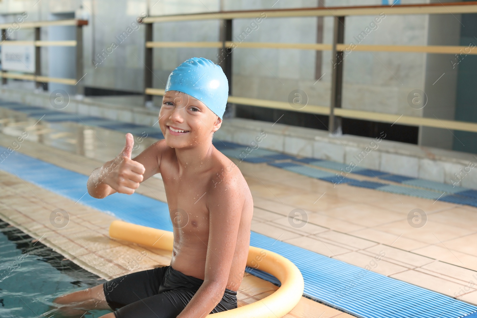 Photo of Little boy in swimming cap near indoor pool