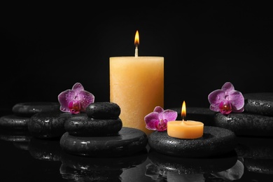 Photo of Composition with candles and spa stones on black background