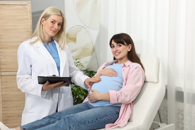 Happy pregnant woman having doctor appointment in hospital