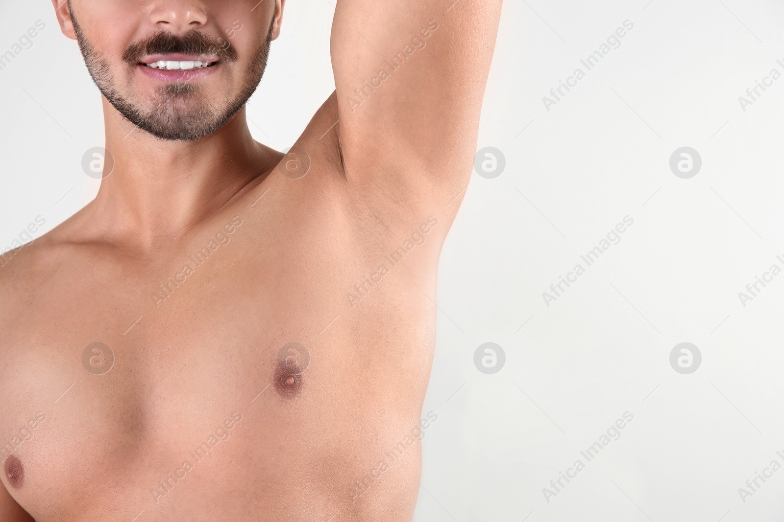 Photo of Young man showing armpit on white background, space for text. Using deodorant