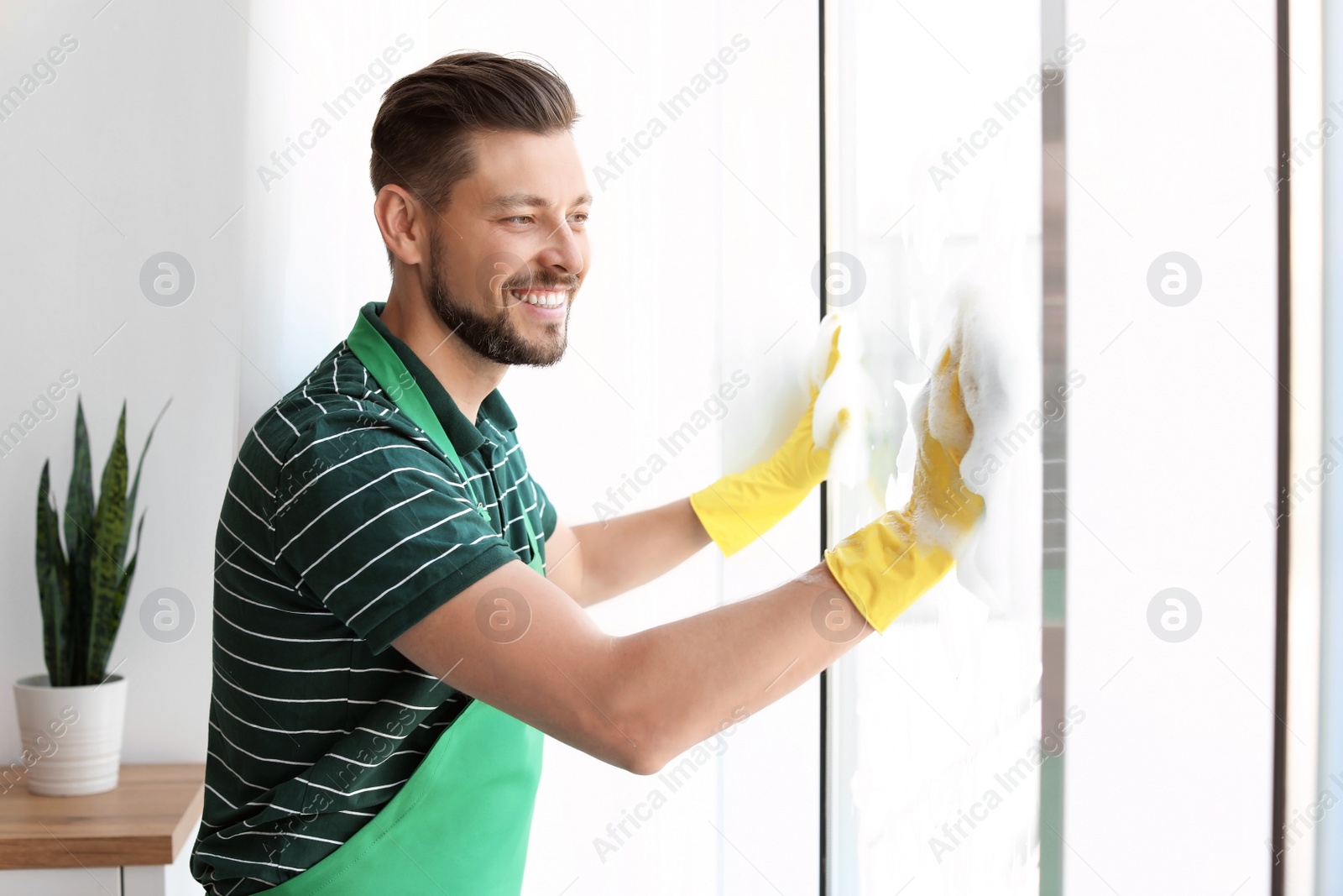 Photo of Male worker washing window glass at home