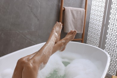 Photo of Woman taking bath with shower gel indoors, closeup