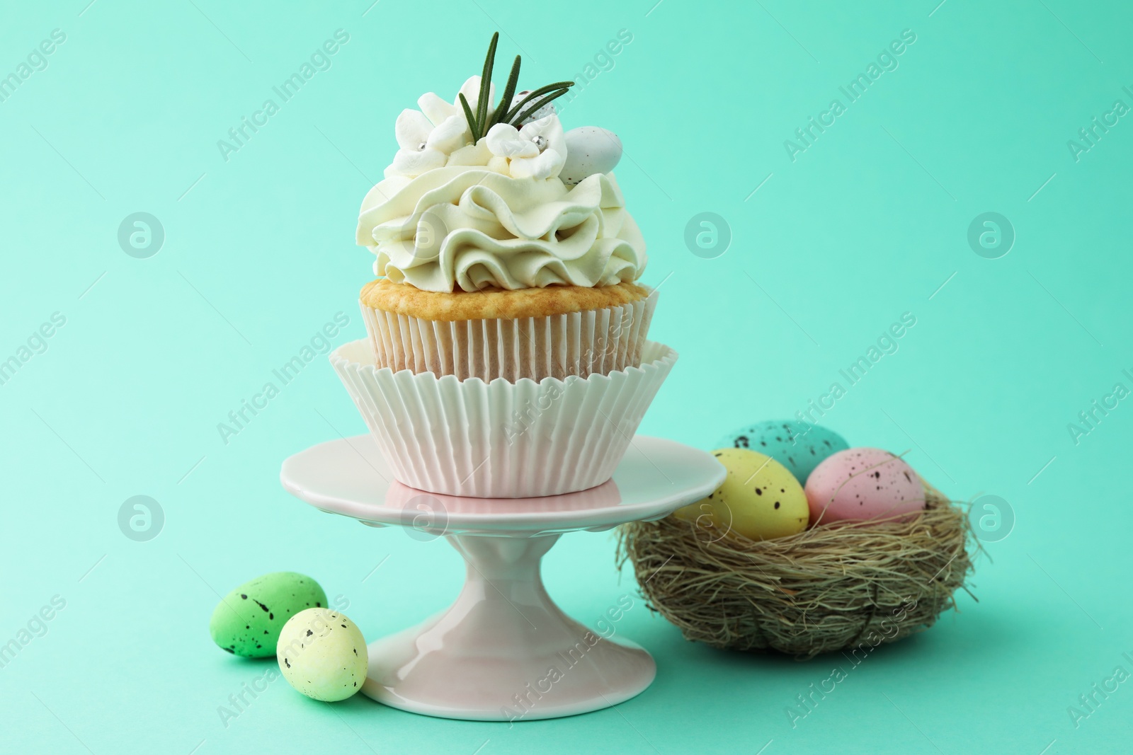 Photo of Tasty Easter cupcake with vanilla cream and festive decor on turquoise background