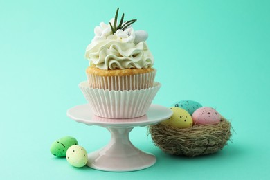 Photo of Tasty Easter cupcake with vanilla cream and festive decor on turquoise background