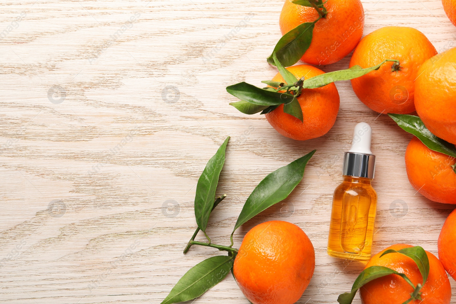 Photo of Bottle of tangerine essential oil and fresh fruits on white wooden table, flat lay. Space for text