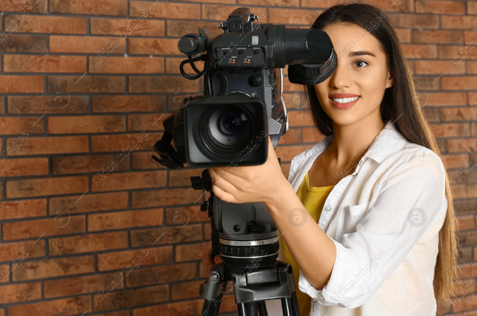 Photo of Operator with professional video camera near brick wall