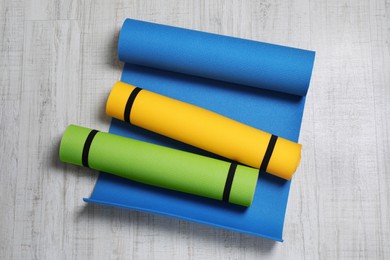 Bright camping mats on white wooden background, top view