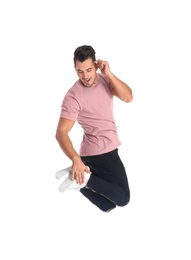 Young man in stylish jeans jumping on white background